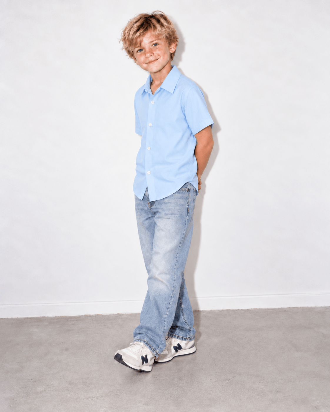 Boy wearing a baby blue short sleeve shirt in a side pose, showing the comfortable fit, classic collar and casual everyday styling.