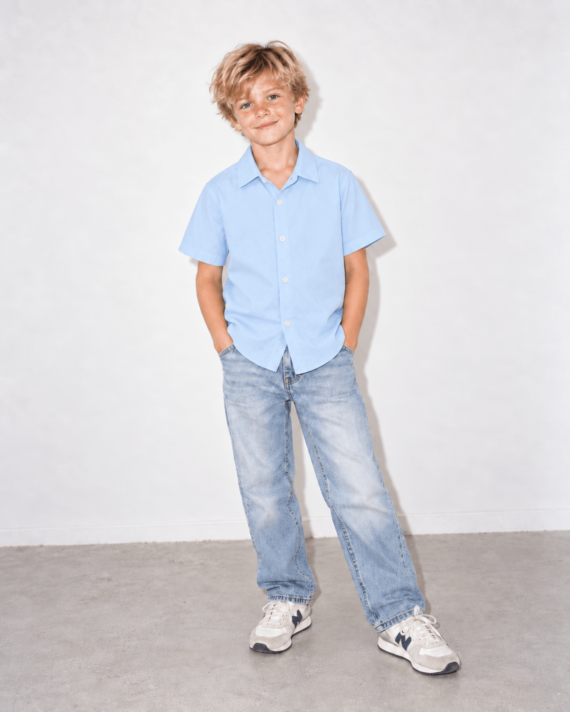 Boy wearing a baby blue short sleeve button-up shirt in a front standing pose, showing the relaxed fit and clean solid color design.