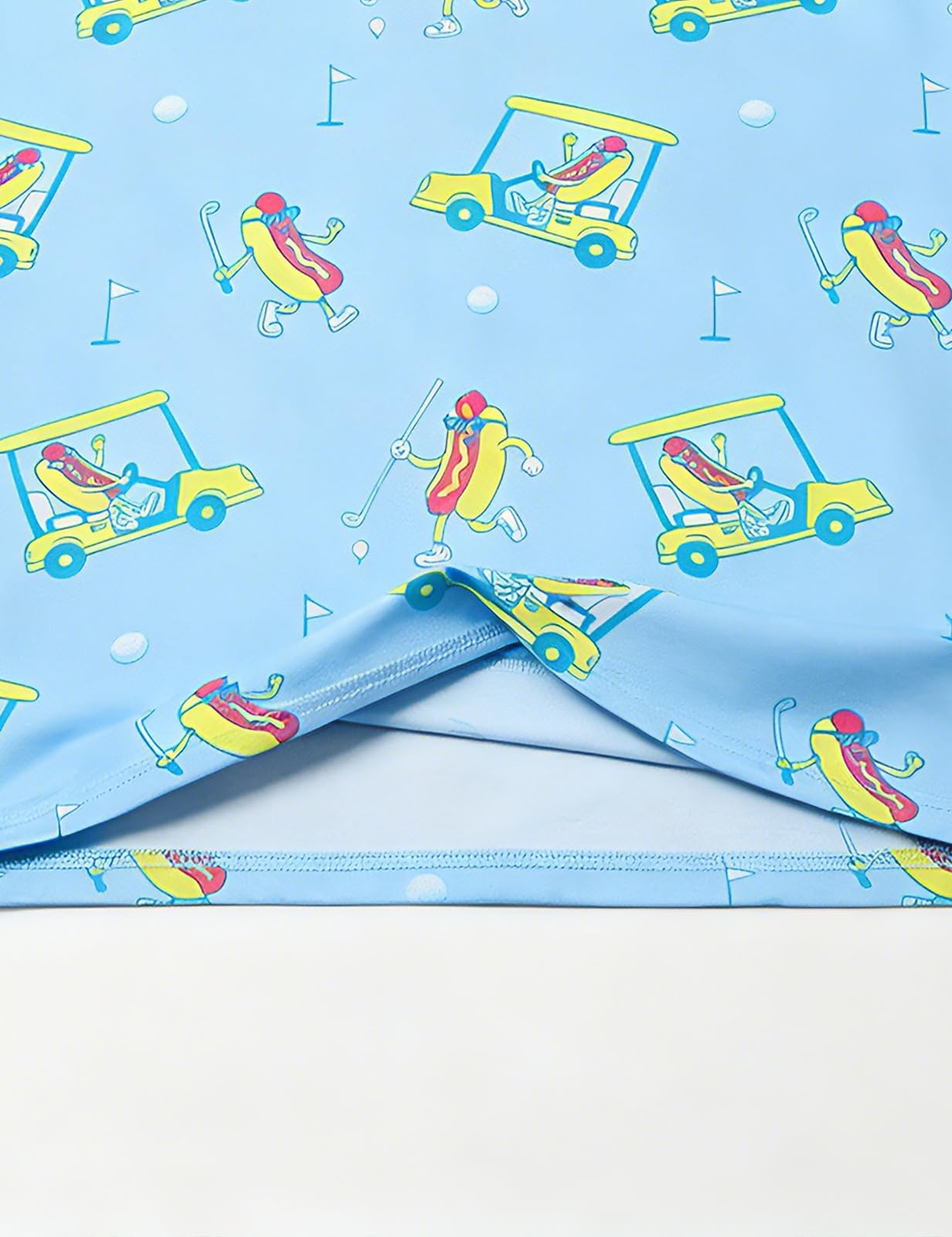 Close-up of boys blue printed polo shirt showing the lightweight stretch fabric, all-over graphic print and hem stitching.