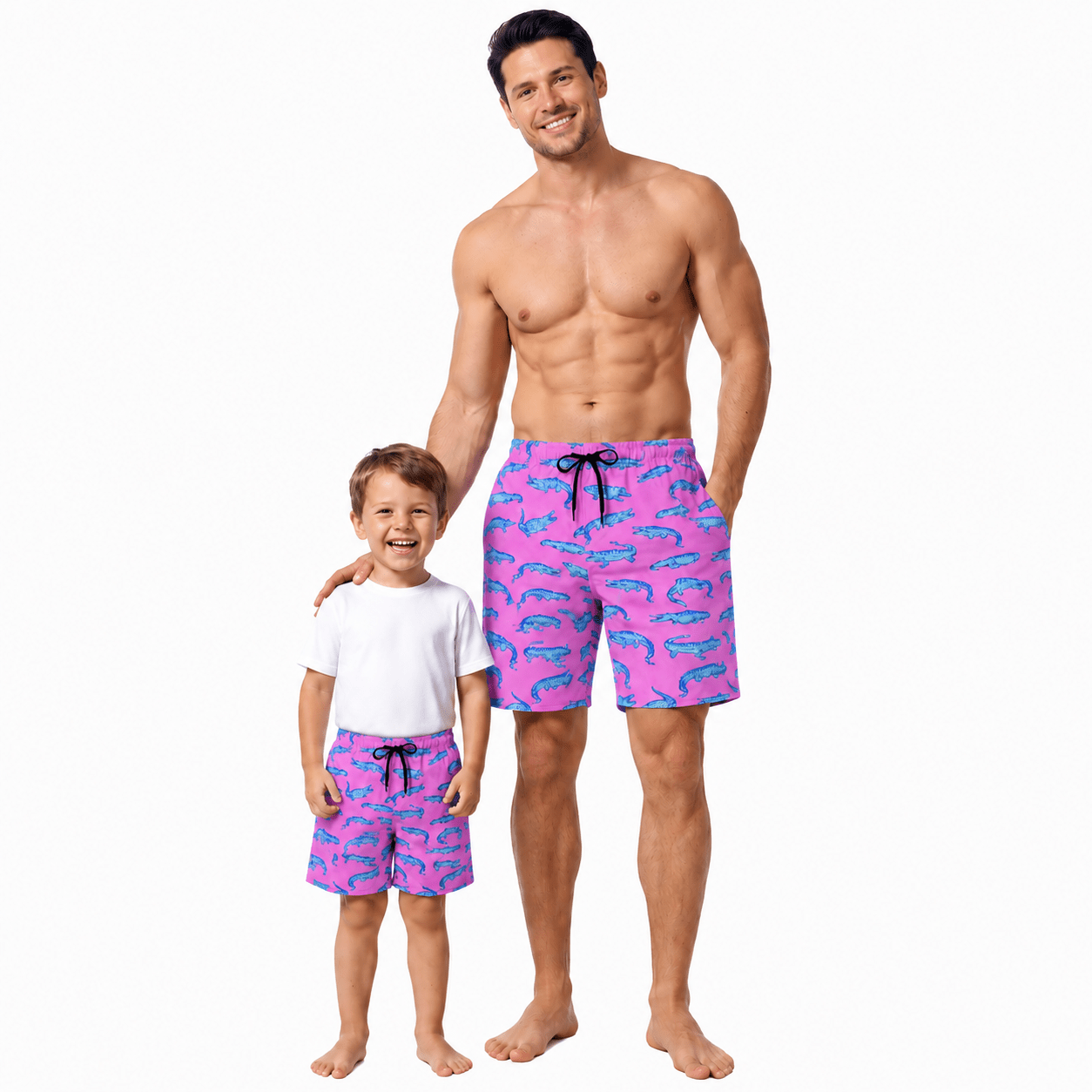Vater und Sohn tragen am Strand passende rosa Krokodilbadebekleidung, perfektes Familienurlaubsoutfit für den Sommer.