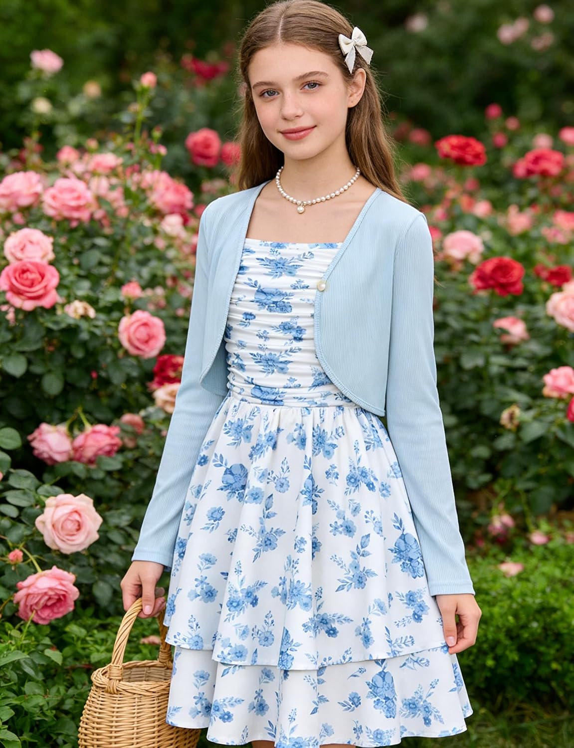 Girl wearing the Blue Floral dress and cardigan surrounded by blooming flowers.