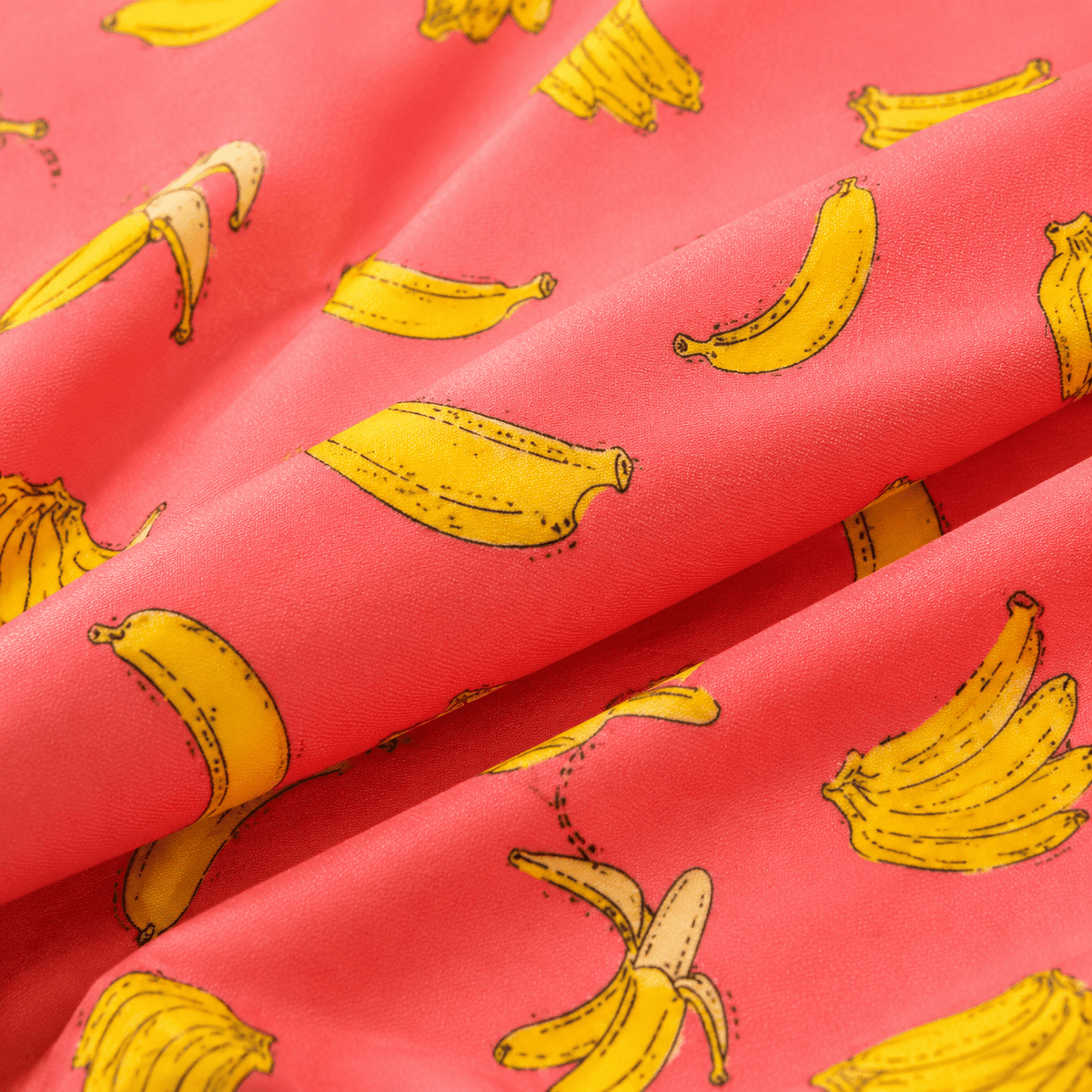 Close up of orange banana print swim trunks showing colorful pattern, lightweight fabric and summer beach style.