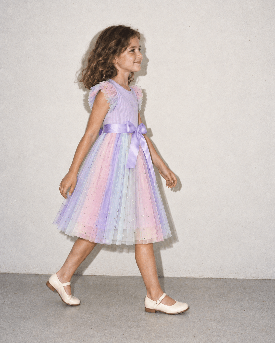 Girl walking in a purple tulle party dress, showing the flowing layered skirt, side silhouette and lightweight movement of the dress.