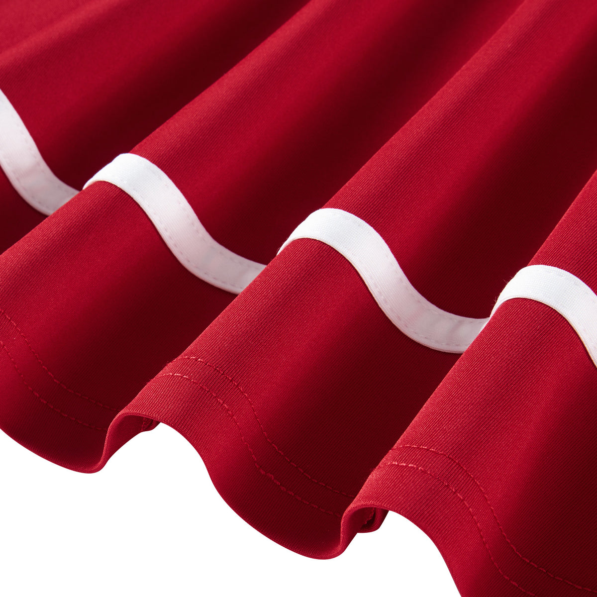 Close-up of the red girls polo dress showing the white contrast piping, long sleeve cuff and flared skirt hem details.