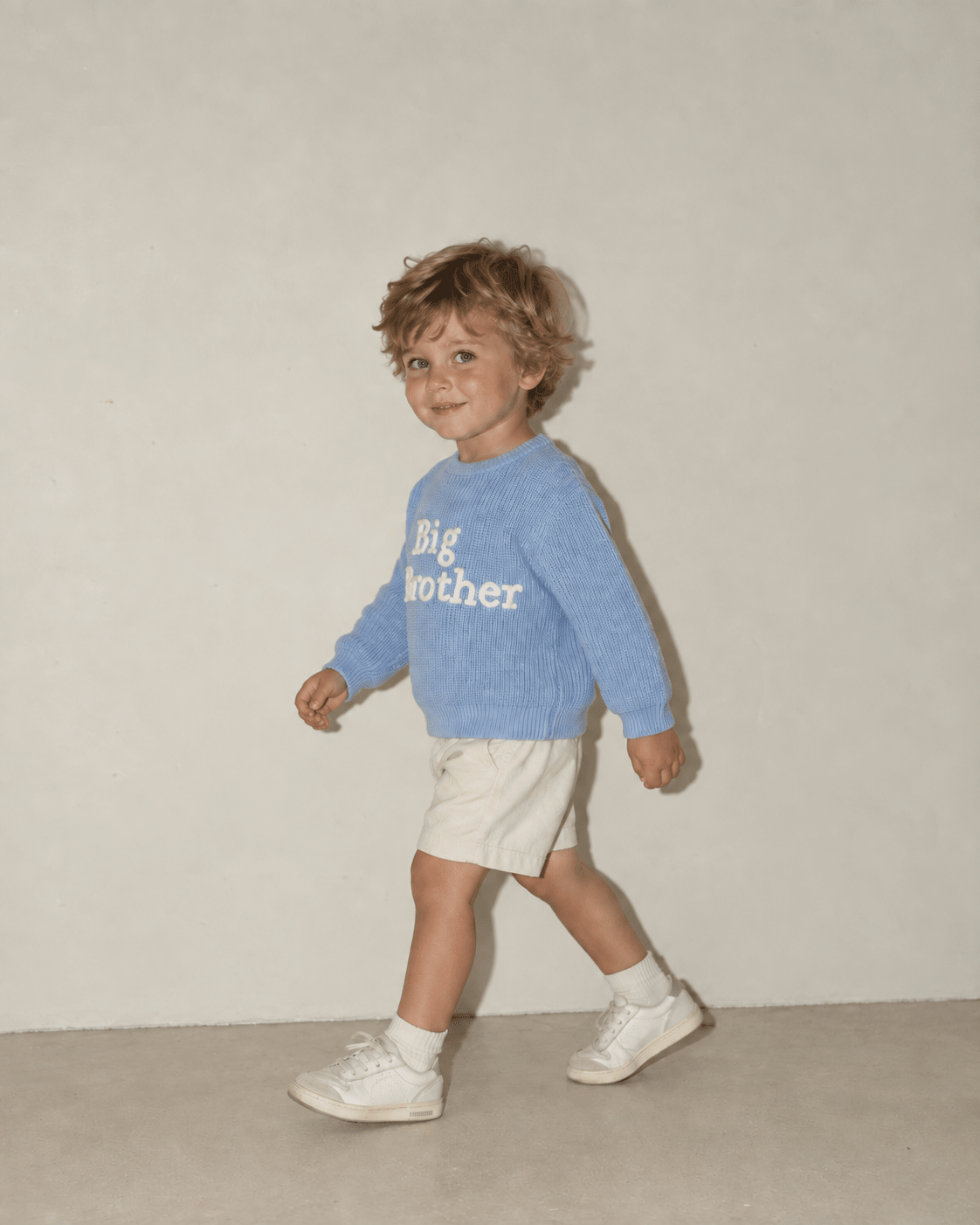 Toddler boy walking in a baby blue Big Brother sweater, showing the side fit, long sleeves and comfortable casual style.