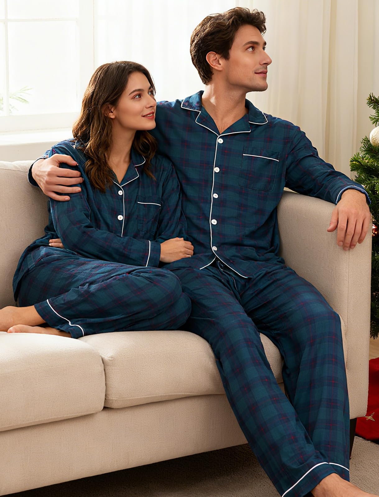 Couple wearing matching navy plaid pajamas relaxing together at home during Christmas holiday