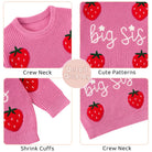Close-up details of the pink Big Sis knit sweater showing strawberry motifs, lettering, ribbed trim and soft knitted texture.