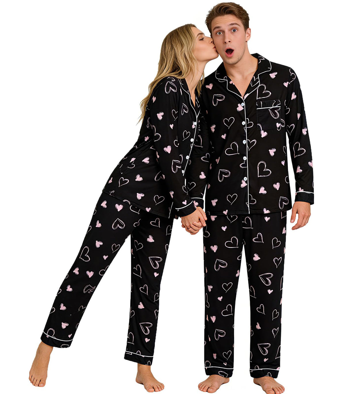 Couple standing together in matching black heart print pajamas, showing the button-down tops and relaxed full-length pants.