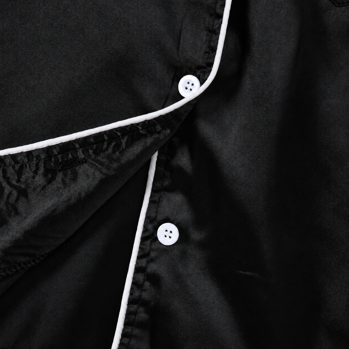 Close-up of the girls black pajama set showing the collared neckline, button front closure and clean stitching details.