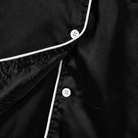 Close-up of the girls black pajama set showing the collared neckline, button front closure and clean stitching details.