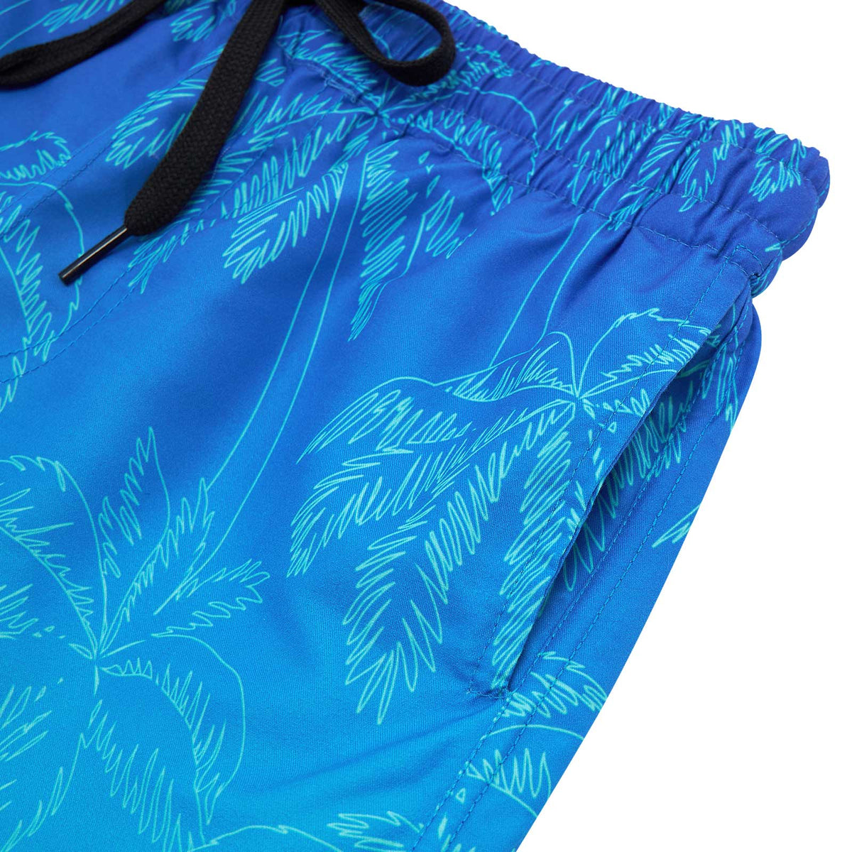 Close-up of blue gradient palm tree swim shorts showing the side pocket construction, seam details and tropical printed fabric.