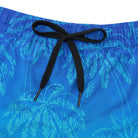 Close-up of blue gradient palm tree swim trunks showing the black adjustable drawstring, elastic waistband and printed fabric.