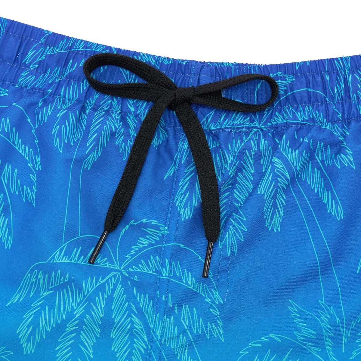 Close-up of blue gradient palm tree swim trunks showing the black adjustable drawstring, elastic waistband and printed fabric.