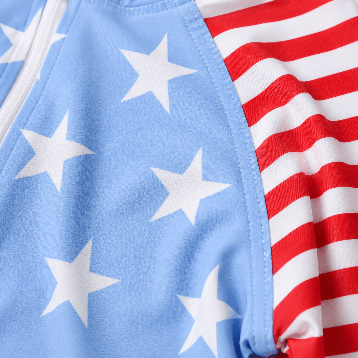 Close-up of toddler Blue Stars rash guard swimsuit showing the star print, striped sleeves, smooth fabric and contrast trim details.
