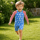 Toddler boy wearing a Blue Stars printed rash guard swimsuit outdoors, showing the long sleeve design and easy zip front construction.