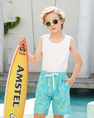 Boy wearing banana print swim trunks with a casual summer outfit, perfect for beach trips, vacations and outdoor activities.