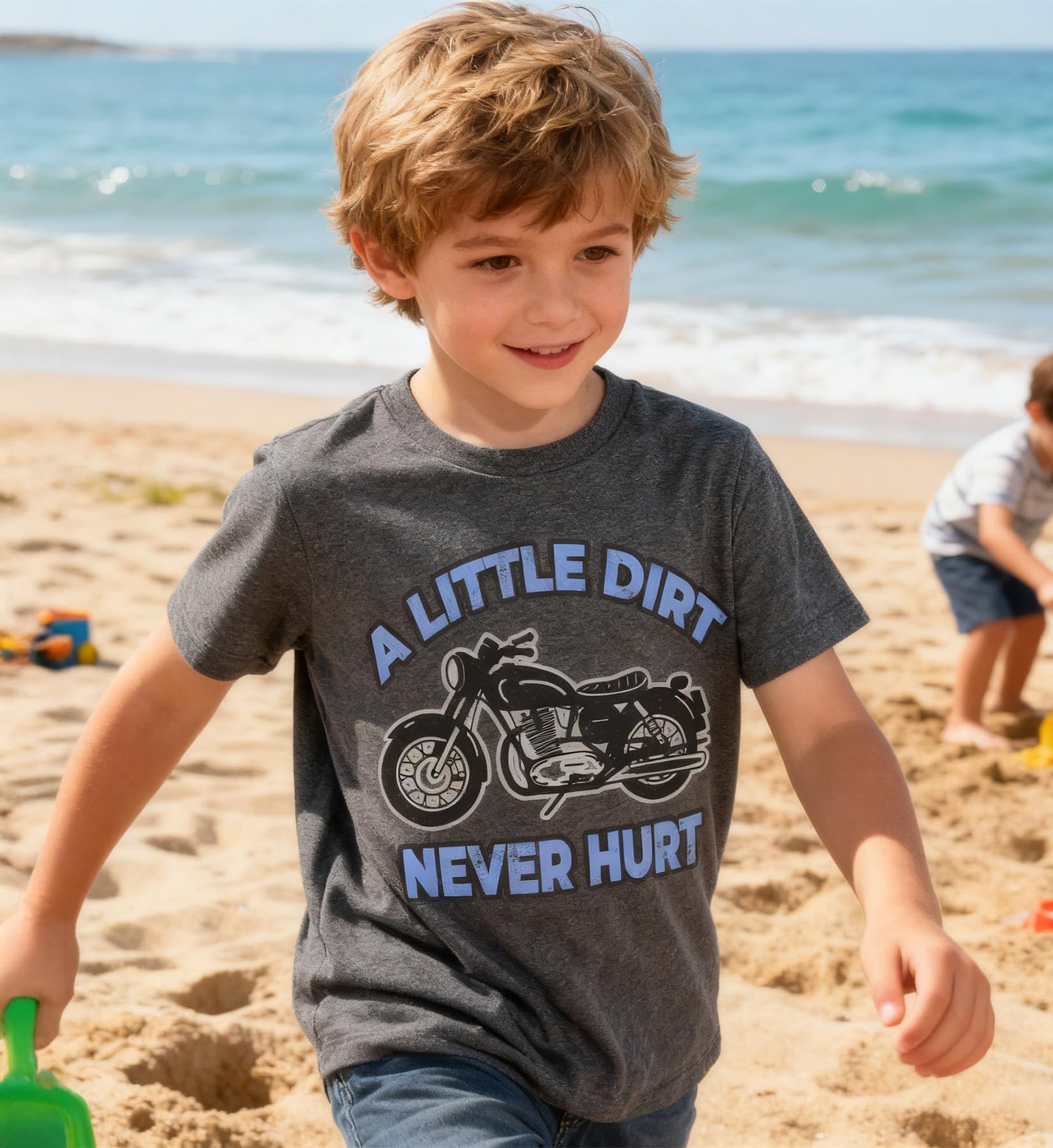 Young boy wearing a gray motorcycle graphic T shirt enjoying a beach day, casual kids summer outfit for outdoor adventures