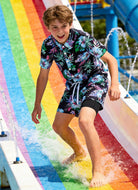 Boy wearing a tropical Hawaiian shirt and swim shorts set during outdoor activities, comfortable summer outfit for kids vacations.