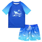 Boys Blue Shark two-piece swim set with short sleeve shark graphic rash guard and coordinating blue swim trunks.
