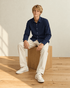 Boy wearing a navy long sleeve polo shirt in a casual sitting pose, showing the versatile style for school and everyday outfits.