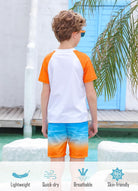 Back view of a boy wearing an Orange Hawaii rash guard swim set, showing the short sleeve top and gradient swim trunks.