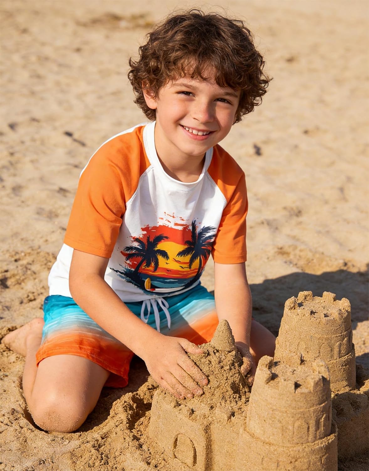 Boy wearing an Orange Hawaii rash guard swim set while building a sandcastle on the beach, styled for summer beach play.