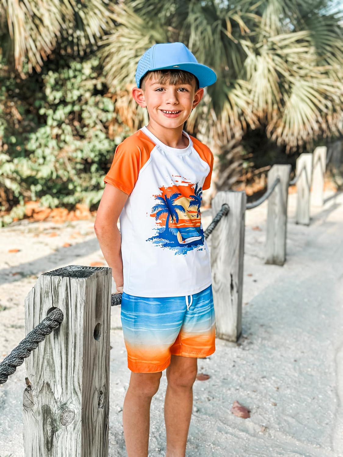 Boy wearing an Orange Hawaii short sleeve rash guard and gradient swim trunks during a casual outdoor summer outing.
