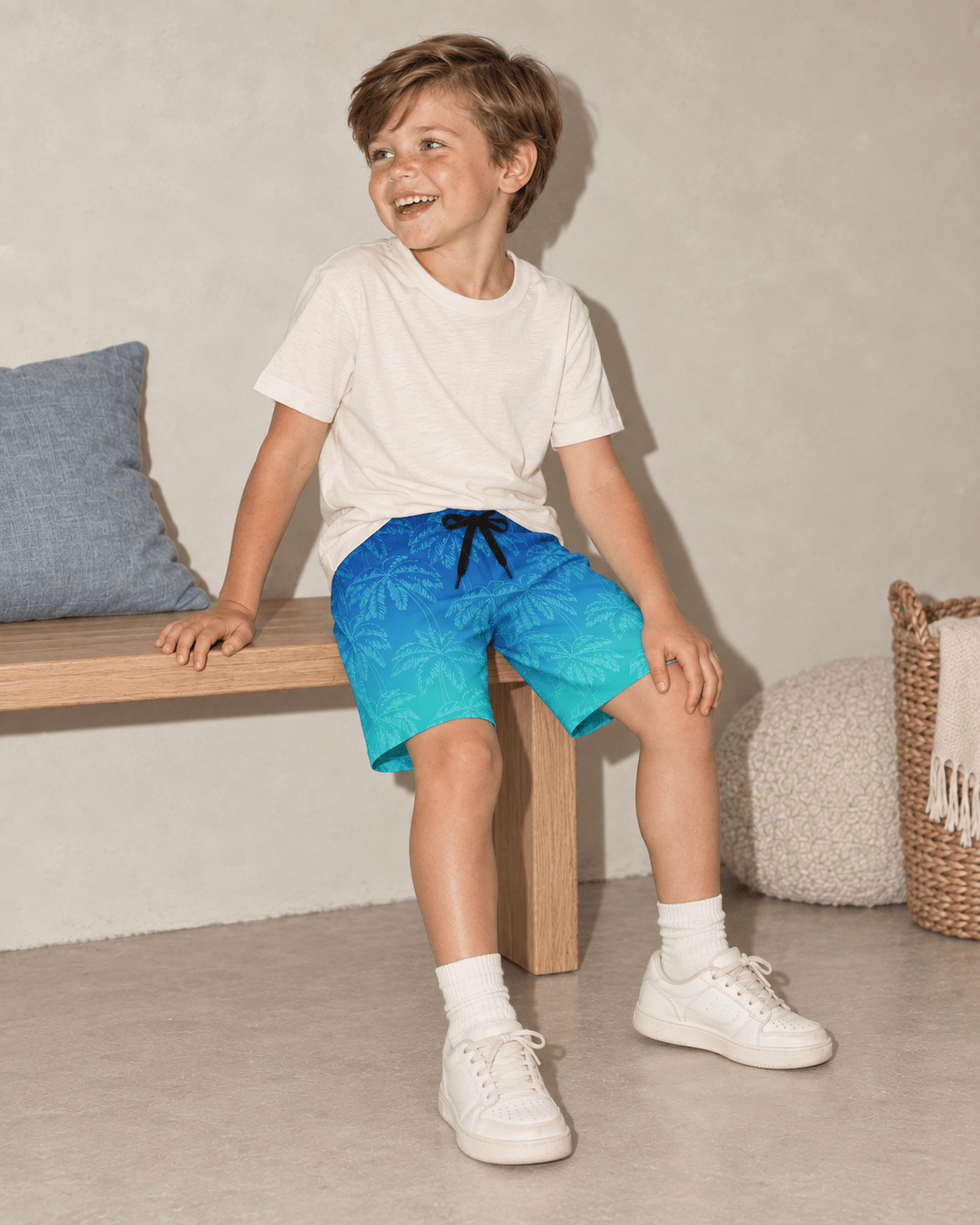 Boy sitting in blue gradient palm tree swim trunks, showing the comfortable fit and tropical design for beach trips, pool days and summer vacations.
