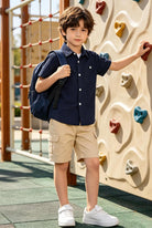 Boy wearing a navy striped polo shirt while climbing at an indoor play wall, featuring lightweight breathable fabric.