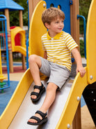 Boy wearing a yellow striped polo shirt while playing on a playground slide, comfortable casual outfit for outdoor activities and everyday wear.