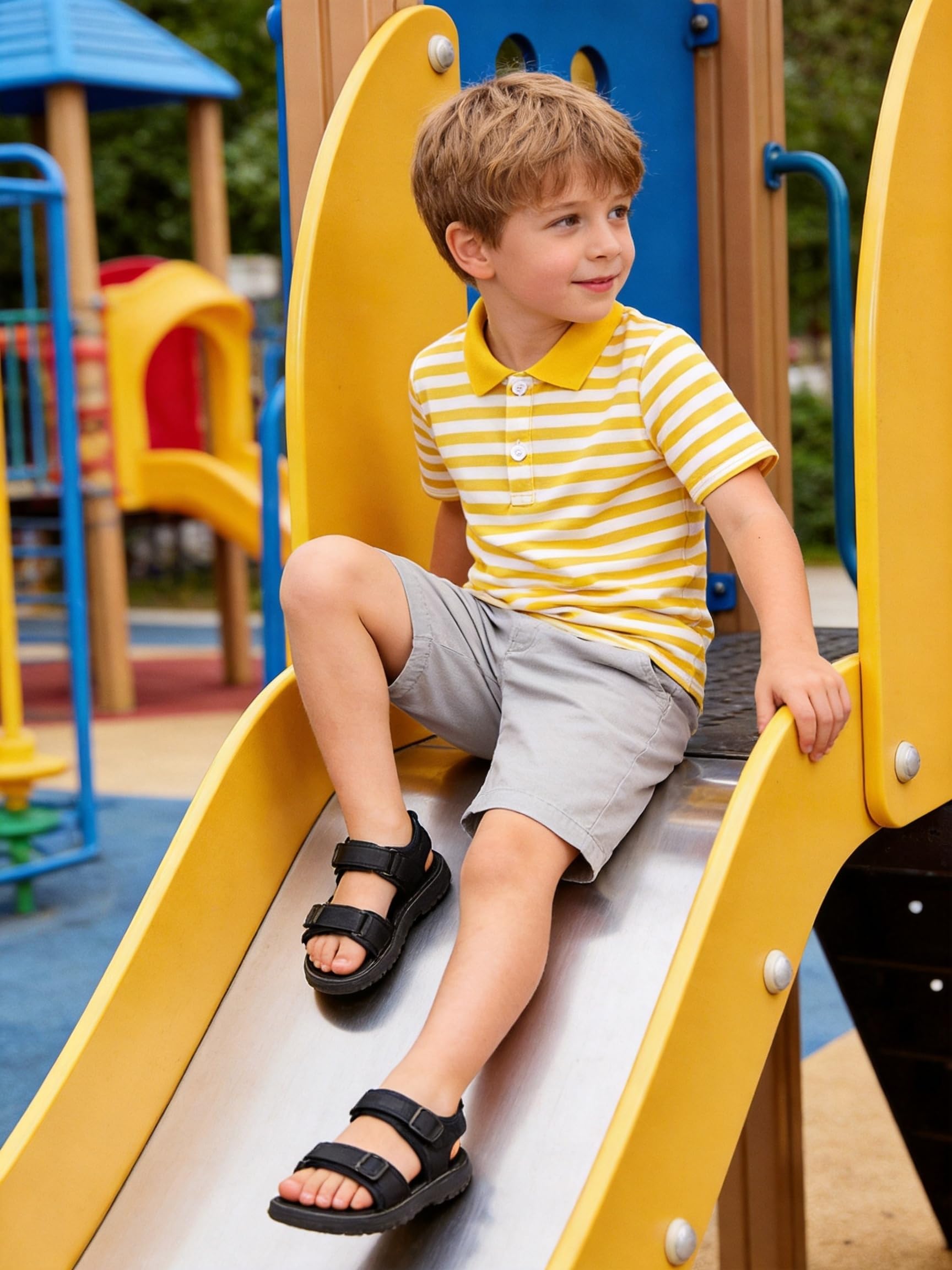 Boy wearing a yellow striped polo shirt while playing on a playground slide, comfortable casual outfit for outdoor activities and everyday wear.