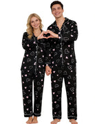 Couple wearing matching Black Heart pajama sets with button-down tops and long pants, designed for comfortable sleepwear and holiday lounging.