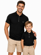 Father and son wearing matching black polo shirts, classic family outfit with comfortable stretch fabric for casual and golf occasions.