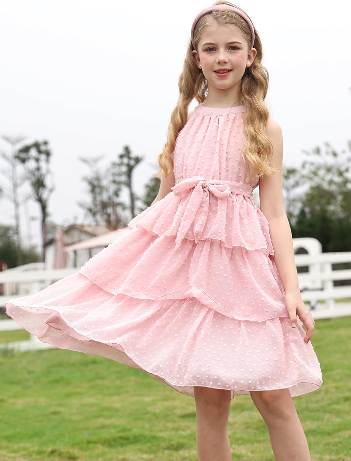 little girl twirling in pink swiss dot tiered party dress with bow waist tie for birthdays and special occasions