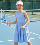 Girl wearing a blue rainbow strap sundress during outdoor activities, comfortable summer dress for kids vacations and playtime.