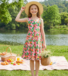 Girl wearing a pink strawberry rainbow strap sundress during outdoor activities, comfortable kids clothing for warm weather.
