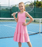 Girl wearing a pink rainbow strap sundress outdoors, showing a cute summer outfit style for travel, play and family occasions.