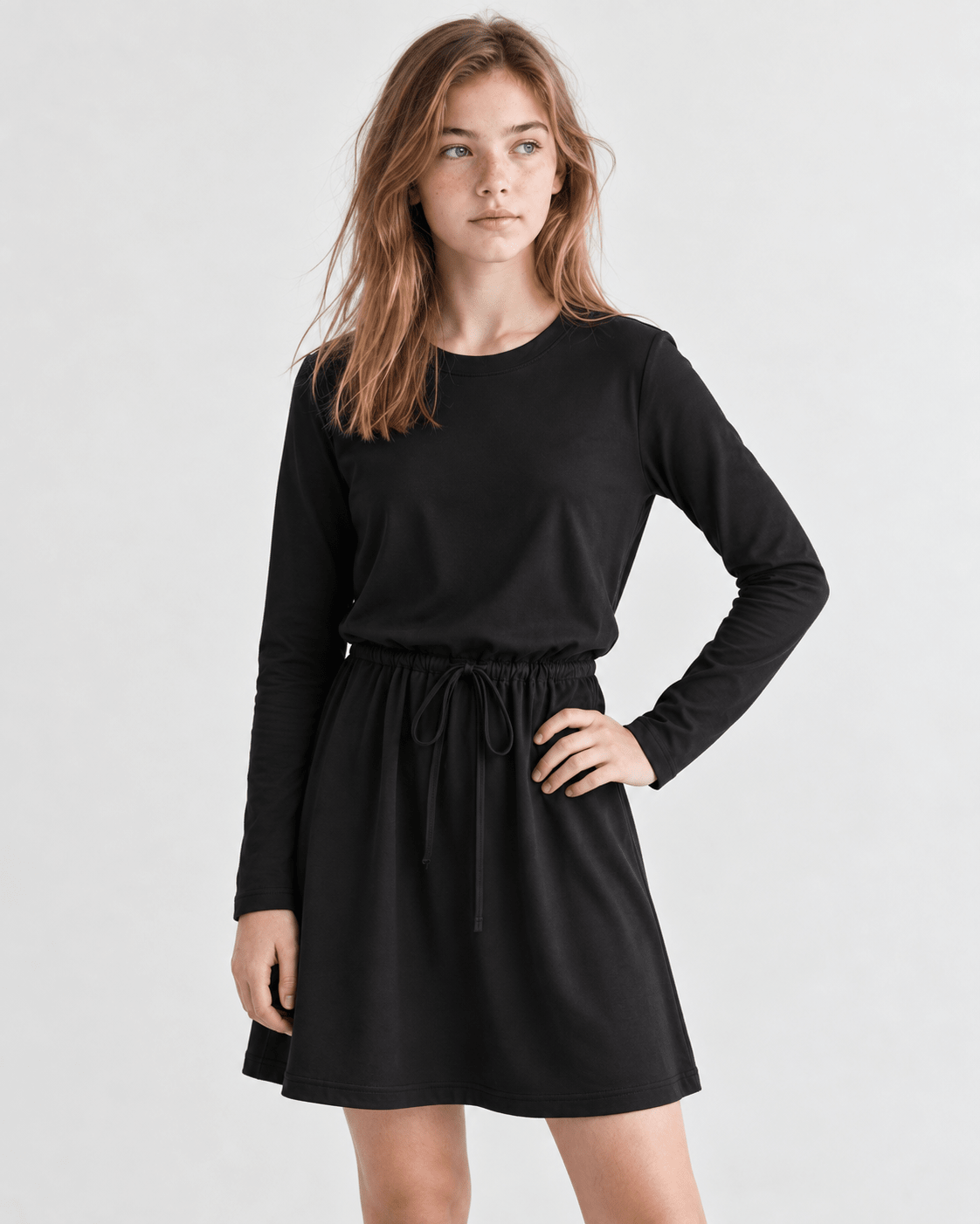 Girl wearing a black long sleeve A-line dress from the front, showing the simple silhouette and comfortable everyday style.