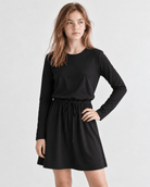 Girl wearing a black long sleeve A-line dress from the front, showing the simple silhouette and comfortable everyday style.