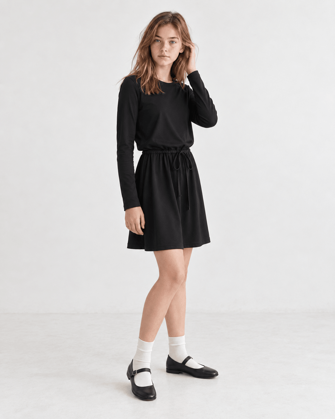 Girl wearing a black swing dress in a side pose, showing the flared A-line shape and long sleeve design.