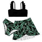 Girls black 3 piece bikini swim set with solid black ruffle top and green tropical leaf print bottoms with matching swim skirt.