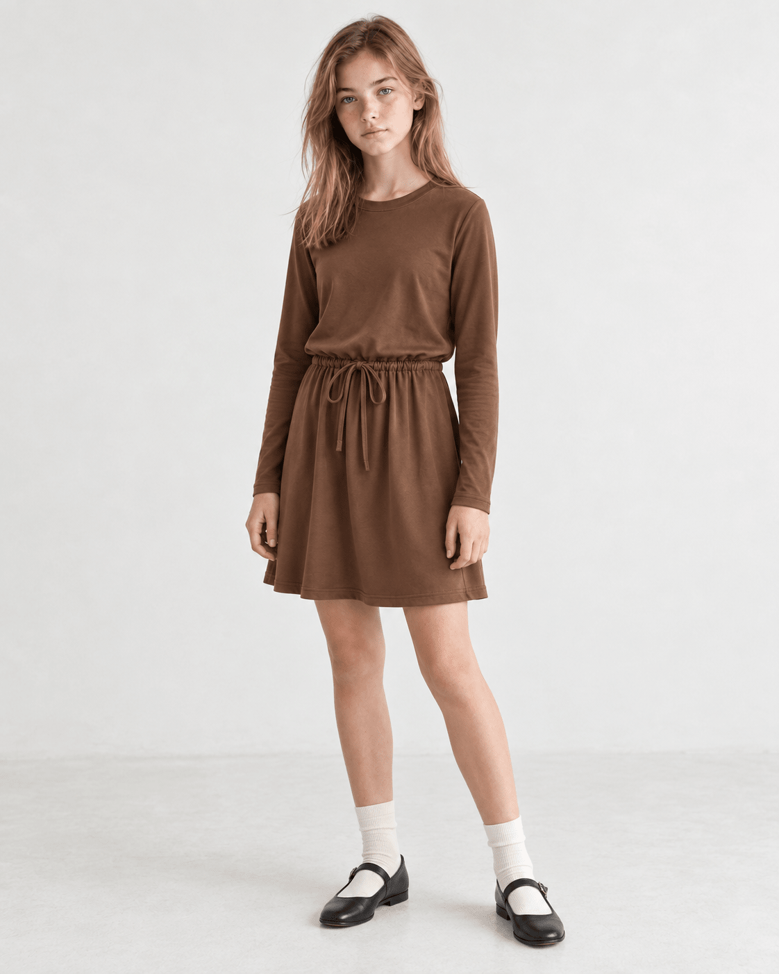 Girl wearing a brown long sleeve swing dress, showing the relaxed A-line fit and versatile style for casual and holiday occasions.