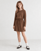 Girl wearing a brown long sleeve swing dress, showing the relaxed A-line fit and versatile style for casual and holiday occasions.