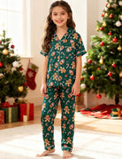 Girl wearing a green Christmas pajama set beside a decorated Christmas tree, showing a cozy holiday outfit for festive family moments.