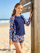 Girl wearing a floral long sleeve rash guard swimsuit set at the beach, showing a comfortable UV swimwear outfit for summer activities.