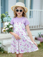 Girl wearing a light purple floral sundress set with a matching T-shirt, sun hat and sunglasses, stylish summer outfit for garden photos, vacations and outdoor occasions.