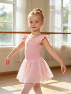 Girl wearing a pink ballet leotard dress while practicing dance movements, flexible kids dancewear for ballet and gymnastics.