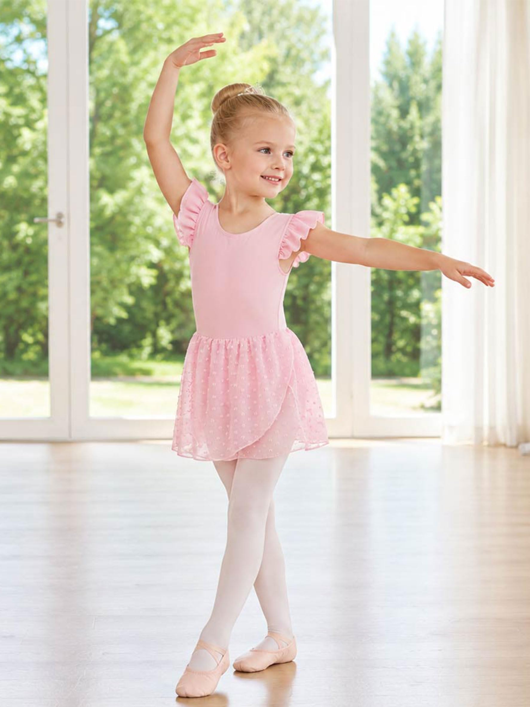 Girl wearing a pink ballet leotard dress while performing a ballet pose, showing the elegant skirt shape and flexible dance outfit for practice and performances.