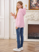 Girl wearing a pink cable knit hoodie sweater indoors, showing the comfortable pullover design and cozy winter styling.