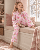 Girl relaxing by the window while wearing a pink Santa Claus pajama set, showing the comfortable fit and cozy holiday sleepwear style.
